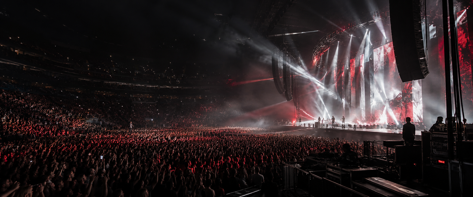 A packed arena concert illuminated in red and white